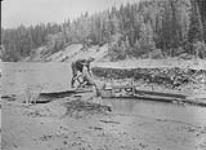 Nutall dumps barrow of gravel into sluice near Barkerville, B.C 1938