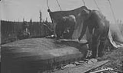 Patching canvas canoe. 1921
