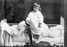 Unidentified child stepping out of a cot 1880