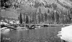 (Relief Projects - No. 155). A tractor drawing logs across Kananaskis River Mar. 1936