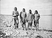 Four Inuit men [Kunannat, Qinuratnaaq, Tasiuq?, Tuluqtuq Mitquittuq] standing by the shore, Baker Lake (Qamanittuaq), Northwest Territories [Nunavut] 1893.