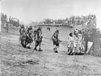 The [Hopi] Snake dancers enter the plaza encircle it four times, and after a series of songs, they proceed to dance with the reptiles. At the right stand the Antelope in front of the booth containing the snake-jars. [north east Arizona] 1922