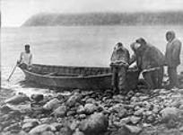 [Alaskan Eskimos] launching a boat off Diomede Island 1930
