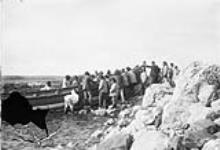 Eskimo and Indians hauling up boat at Fort Chimo, [Que.] 1896