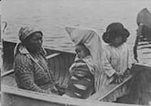 [Atikamekw woman, infant on a cradleboard and young girl in a canoe]. Original title: Tete de Boule papoose, Sanmaur, P.Q c.a. 1928.