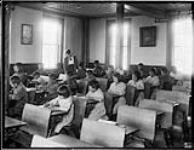 Intérieur d'une salle de classe, étudiants travaillant à leurs pupitres, Pensionnat indien de Brandon (Manitoba), 1946 1946.