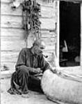 Louis Vallee repairing his birch bark canoe n.d.