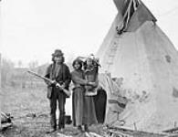 [Saulteux couple, James Quesace on left, with their child in a cradleboard, vicinity of the Upper Assiniboine River, Manitoba] Saulteux Indians from Upper Assiniboine River 16 Oct. 1887