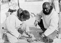 (Hudson Strait Expedition). Eskimoes eating raw seal meat, Port Burwell, Quebec [Nunavut], 22 April 1928 April 22, 1928.