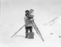 [Unidentified Inuk man looking through the lens of a movie camera on a tripod, Kangiqsujuaq, Nunavik] Original title: Eskimo with Mr. George Valiquette's movie camera, Wakeham Bay, Quebec 1928.
