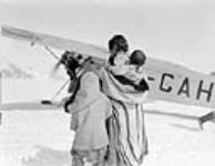 Inuit woman child and baby standing in front of a Fokker 'Universal' aircraft at Base 'C' Wakeham Bay, Quebec [Nunavut], 1928 1928.