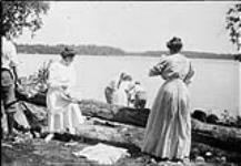 Group preparing for a picnic beside felled tree n.d.