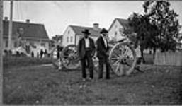 Two Cree men and a boy standing in front of cannons at the Hudson's Bay Company Post in Moose Factory, Ontario 1905