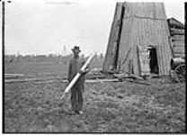 A man [holding] a torpedo for oil drilling 1904