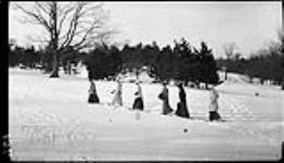 Six girls (snowshoeing) in single file, High Park Feb. 1914