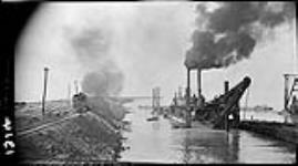 Dredges and scows at Port Weller by pier and engine [during construction of the] Welland Canal, [Ont.] 18 Sept. 1914