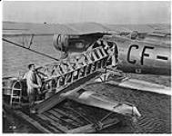 [Men loading hull of boat into Fairchild Super 71 aircraft CF-AUJ of Canadian Airways Ltd., N.W.T. Taken 1934-1939.] [1934-1939]