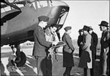 Squadron-Leader Wray signing the book after trial with the first Bristol Bolingbroke in RCAF, at RCAF station, Ottawa, ONT c.a. 1939.
