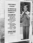 Un aviateur non identifié vérifie son uniforme dans un miroir avant de passer les portes de sortie à une station de l'ARC July 28, 1943