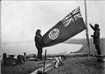 Templeman and F.W. Maurer hoisting a flag during the celebration of Dominion Day at Rogers Harbor, Wrangell Island, [Alaska], 1 July 1914 1913 - 1914
