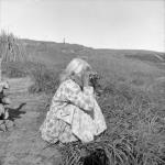 [A First Nations woman, possibly Cree, looking through binoculars at the Norseman] Original title: An Indian woman at Great Whale River was very interested in a close-up look of the Norseman without getting too close herself 1949