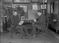 Thomas T. Hawkins (right), portraying a "Case Examiner", checking the sortation effort of John H. (Jack) Roberts'annual examinations as a Railway Mail clerk ca. 1920