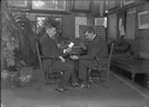 John H. (Jack) Roberts (left), apparently identifying types of keys used by Railway Mail Service with Thomas T. Hawkins ca. 1920