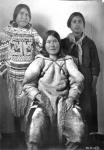 Photograph of three young Inuit women in a shallow setting [left to right: Kajurjuk, Misiraq (sitting), Elizabeth Unurniq (Tapatai) at the Hudson's Bay Co building] 1926.