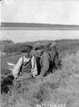[Quatre garçons assis sur une colline gazonnée, Fort McPherson (Territoires du Nord Ouest), 1928] 1928