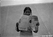 Nu-Koad-lah's wife [Ee-Too-Tsia] looking at her picture in magazine 1925