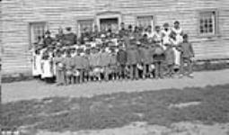 Officials and school children outside the Fort Providence Indian Residential School vers 1920