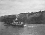 Dredge in tow of S.S. "Wilbur Crimmin" en route to Stewart River, Y.T., c. 1905 ca. 1905.