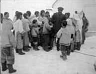 Distribution de cigarettes à des jeunes filles inuites. Pangnirtung (T.N.-O.), vers 1944 Vers 1944