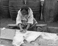 Inuit woman at Pangnirtung, Baffin Island, Cumberland Gulf, employed by Hudson Bay Co. to cut blubber off skin of white whale. c. 1924 1924