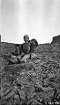 Woman sitting on a rocky hill with a small child and a baby [They are probably from Greenland.] Août 1925.