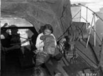 Making a pair of sealskin shoes. [Unidentified woman from Greenland stretching a "kamik", High Arctic region.] 1925
