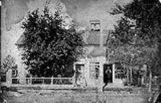 [F. Iveson house and business, Metcalfe, Ont.]. Frank one of Timothy's four sons stands in doorway [between 1880 and 1885]