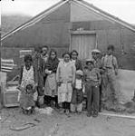 Sam Crow and his immediate family [Left to right: Caroline Sappa, Elizabeth Sappa, Charlie Sappa, Josie Cookie, Mary Cookie, Betsy Crow, Mina Crow Inuktaluk, Charlie Crow, Paulossie Sukku Nuktie, Sam Crow and Josie Crow] and some relatives outside the warehouse of the Hudson's Bay Company Outpost at Richmond Gulf, [P.Q.] 1949.