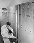 A plant worker is shown putting on shoes to protect against radioactivity / Un travailleur d'usine se chausse pour se protéger contre la radioactivité, Chalk River (Ont.) Nov. 1947