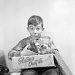 A boy is delighted to open his parcel and to find a pair of skates Jan. 1957.