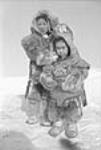 [Otuqayuaq (rear) and Rosie Iggi (front). This photograph was taken at a fox trading company in Kingayualik near Arviat (formerly Eskimo Point). Inuit life is changing these days, and it's very different from how we used to live. Today we can only buy things with money and try to support our children and grandchildren.] [Février 1950] 1950