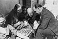 Dr. Norman Bethune (centre) watching a game of checkers 1937