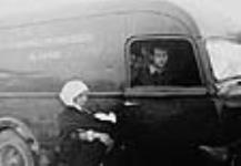 Refugees beside an ambulance of the Canadian Blood Transfusion Unit during the Spanish Civil War. Hazen Sise is sitting in the passenger seat of the ambulance ca. 1936 - 1938