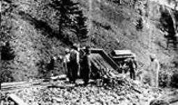 [Group of East Indians dumping trucks of debris, Frank, Alberta.] [c 1903]