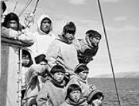 [Inuit awaiting medical examination aboard C.G.S. "C.D. Howe" at Sugluk, Nunavik, watch helicopter landing], July 1951 July 1951.