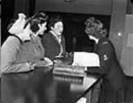 Leading Wren Evelyn Kerr (right) of the Women's Royal Canadian Naval Service (W.R.C.N.S.) interviewing British wives of Canadian sailors, Canadian Wives Bureau, London, England, 30 November 1944 November 30, 1944.