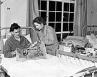 Mrs. M.A. Simpson of the Canadian Red Cross assisting Lance-Corporal L.D. Turner with needlepoint work, No.11 Canadian General Hospital, Royal Canadian Army Medical Corps (R.C.A.M.C.), Taplow, England, 14 December 1944 Deember 14, 1944.