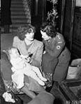 Assistant Matron Kathleen Hurley helping war bride Mrs. H.F. Whitmore and her son Mervin, who are en route to Canada. Maple Leaf Club, London, England, 4 December 1944 December 4, 1944.