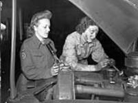 Private Helen Brymer, Canadian Women's Army Corps (C.W.A.C.), watching Private Dorothy Lowry check the battery of her vehicle at the Chelsea & Cricklewood garage, England, 7 July 1944 July 7, 1944.