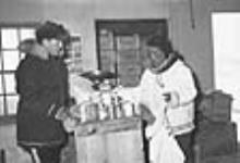 A non-Inuit man and an Inuit man in the Hudson's Bay Company store in Inukjuak (Port Harrison), Quebec 1947-1948.